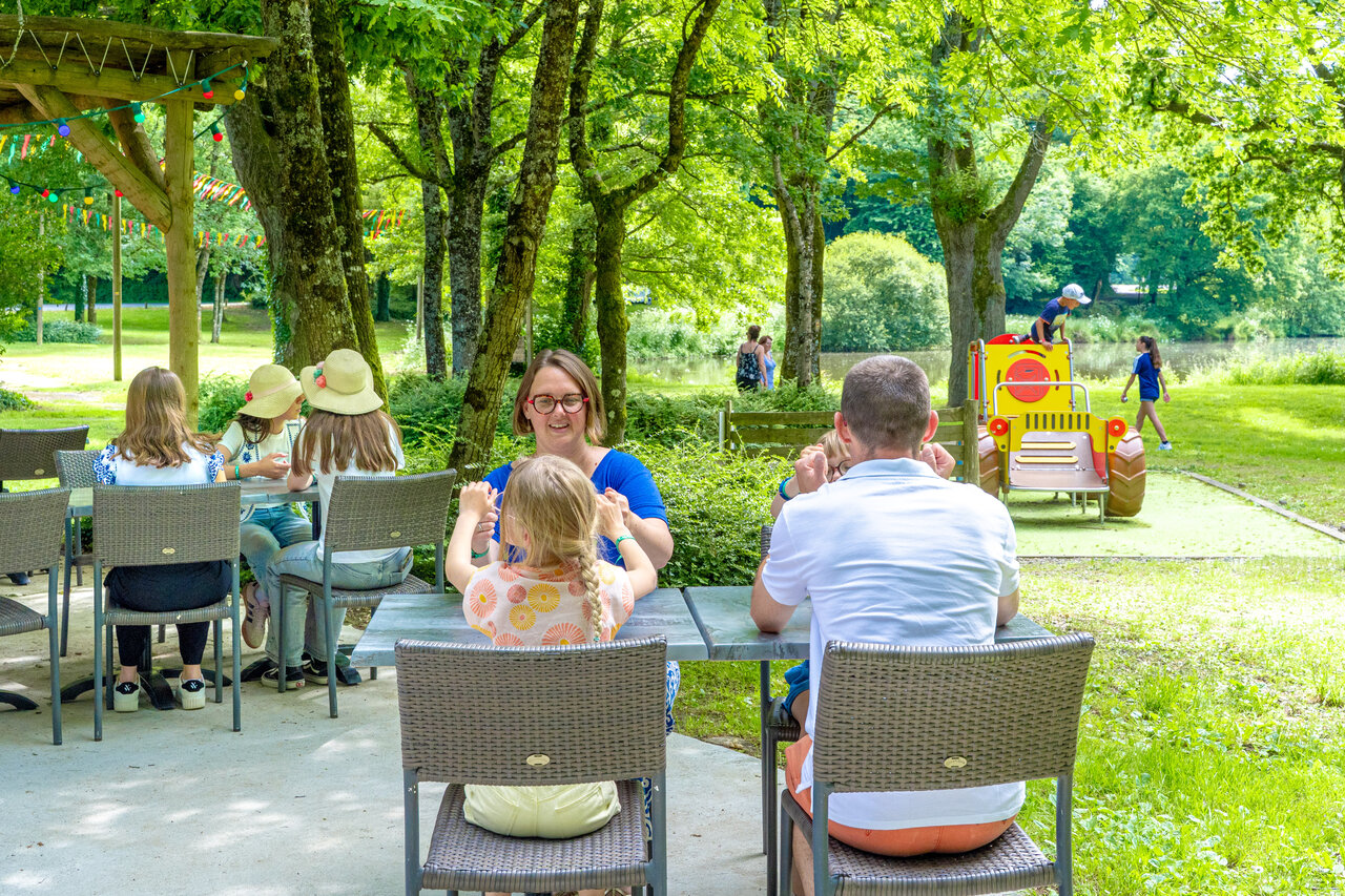 Gezinnen op buitenterras, kinderen spelen bij meer, CAPFUN Breteche camping.