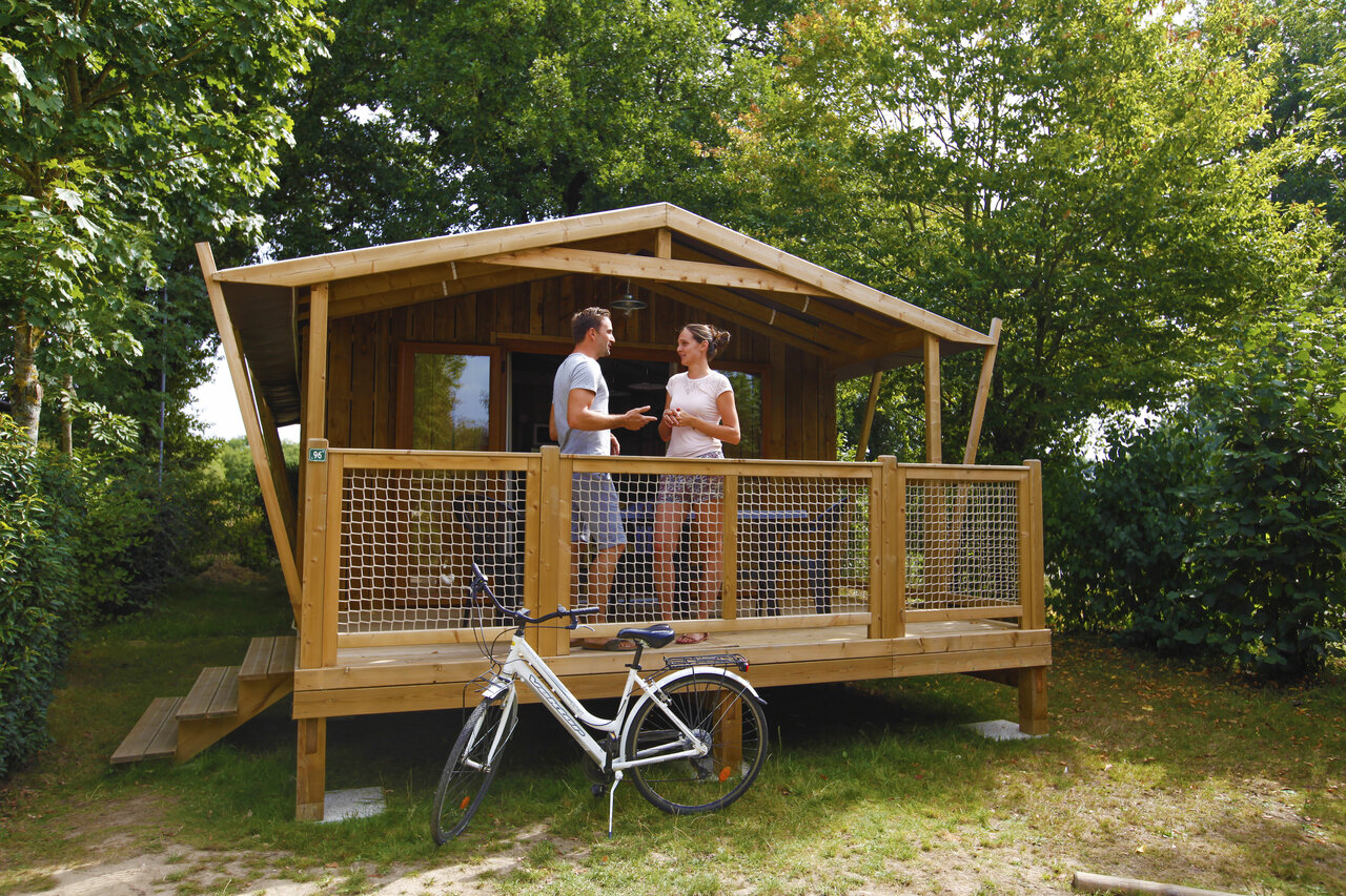 Houten chalet, stel op terras, fiets bij CAPFUN Breteche Les Epesses (85).