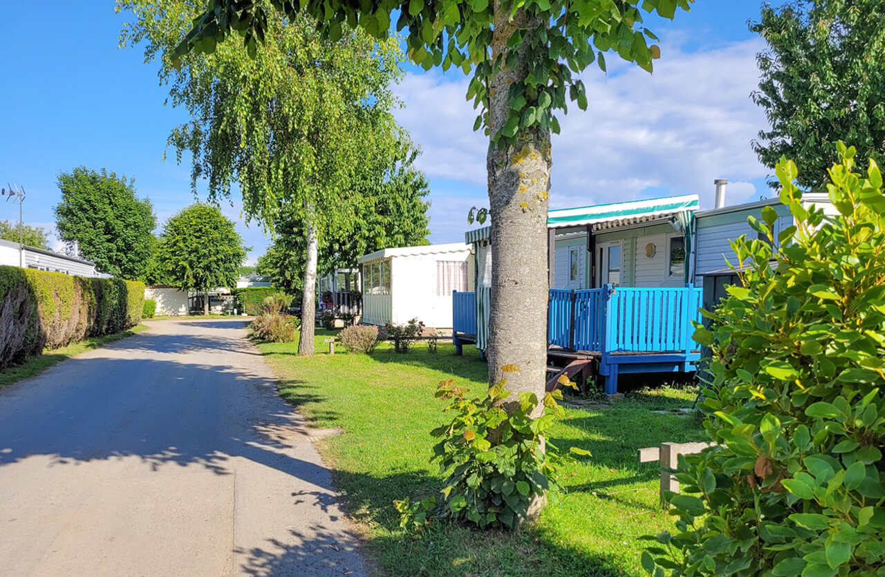 Stacaravans met blauwe terrassen en groene laan op CLICOCHIC Brise de Cabourg.