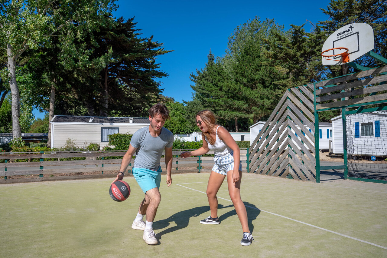 Koppel speelt basketbal op multisportterrein op camping CLICOCHIC Cabanes d'Ol�ron.
