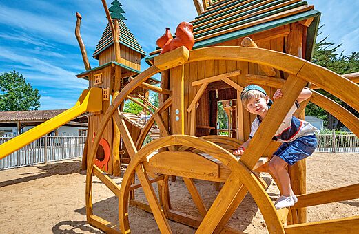 Houten speeltuin met glijbaan en kind op camping CLICOCHIC Cabanes d Oléron in ST GEORGES D'OLERON (17).