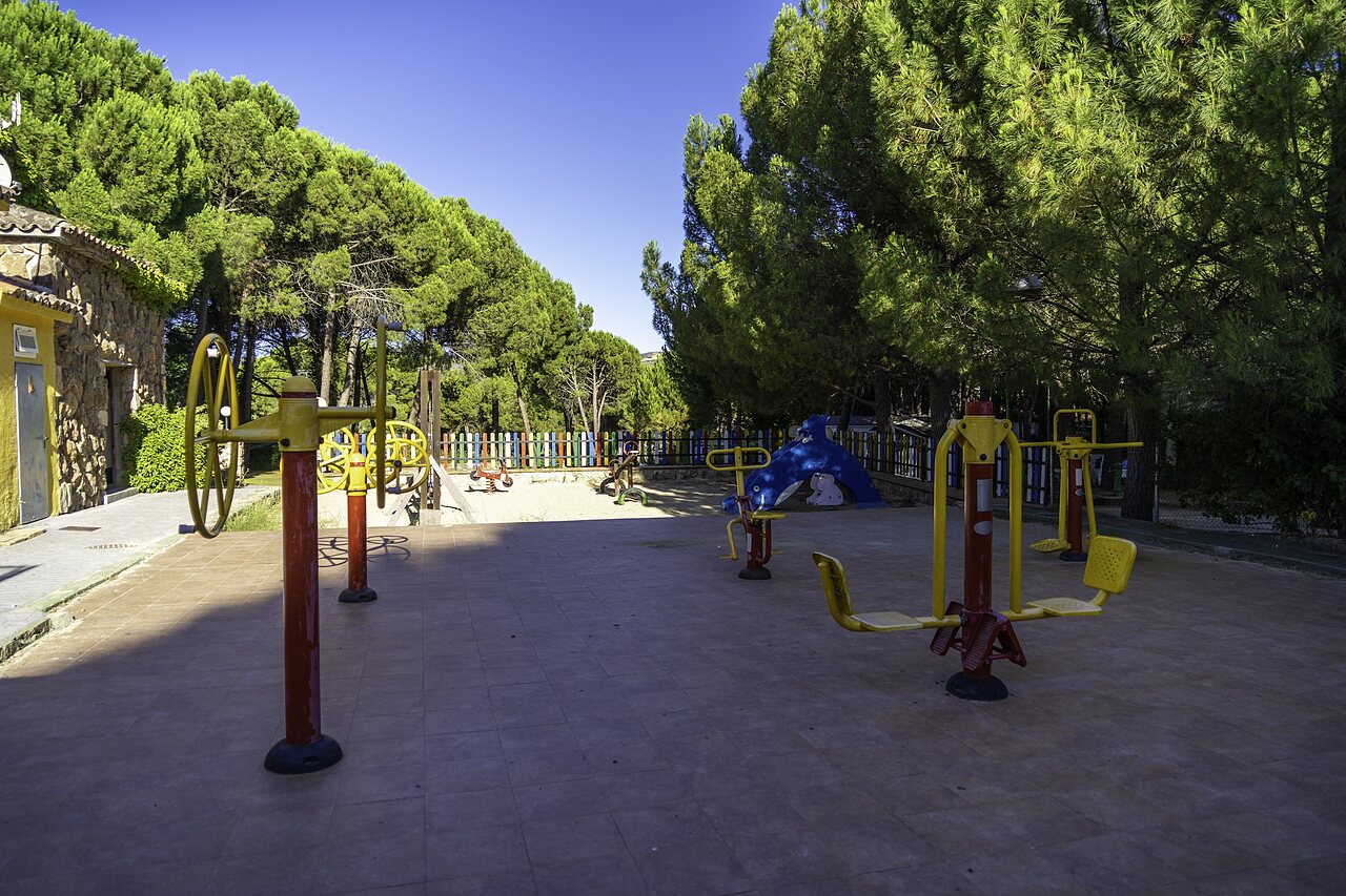 Buiten fitnessapparatuur en speeltuin op camping CAPFUN El Canto La Gallina in Valdemaqueda (Madrid).