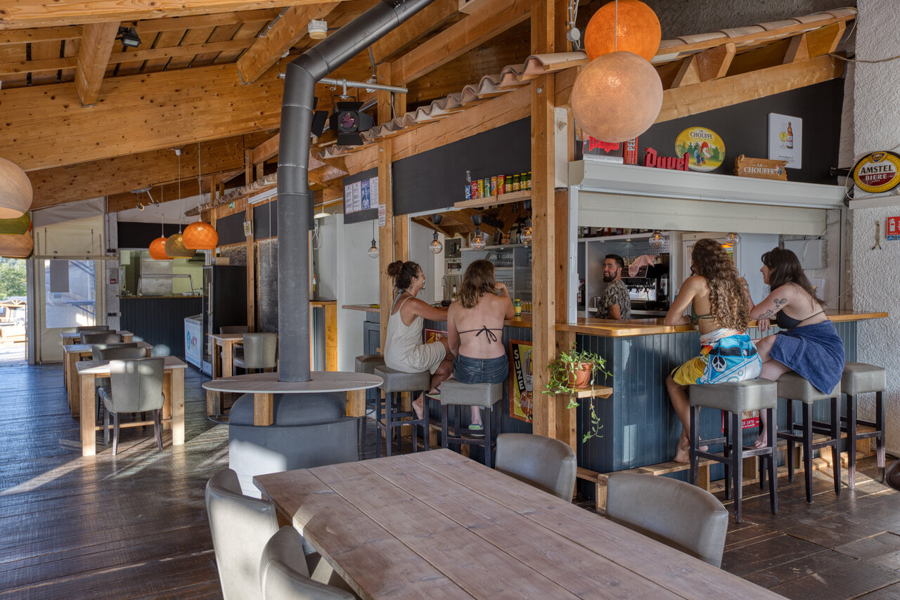 Levendige bar en restaurant, gasten en barman op camping CLICOCHIC Castillon de Provence.