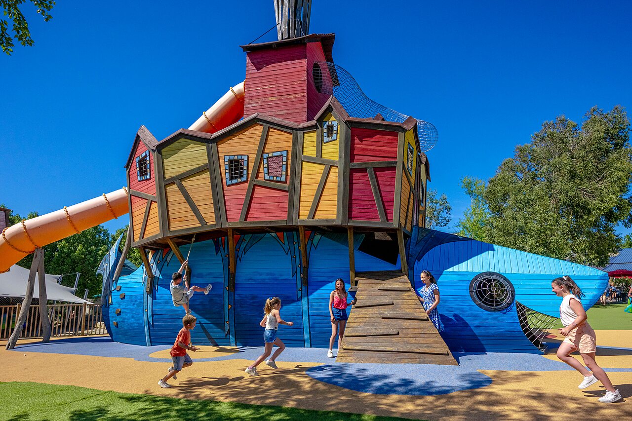 Grote kleurrijke speelstructuur met glijbaan en kinderen op camping CAPFUN Cenic in PENESTIN (56).