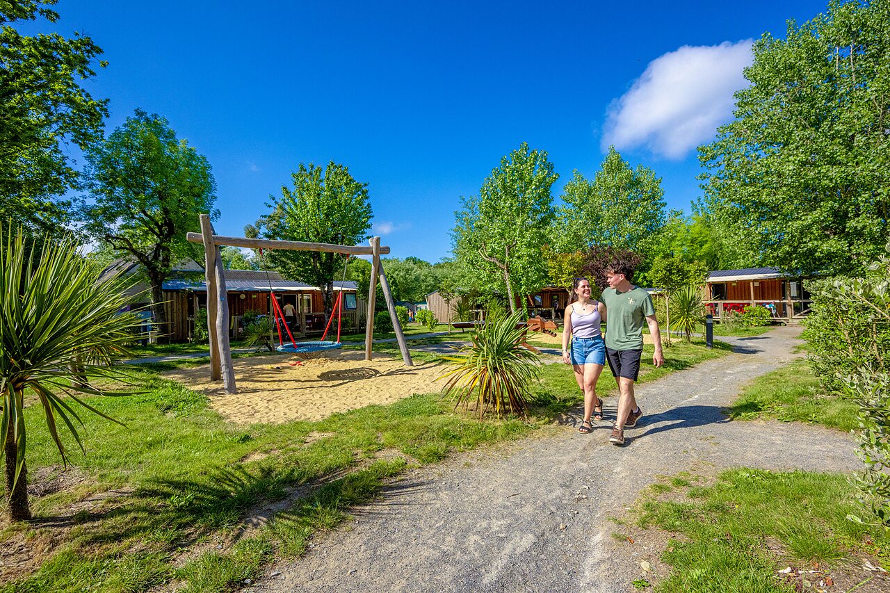 Speeltuin met schommel, wandelend stel, stacaravans op camping CAPFUN Cenic in PENESTIN (56).