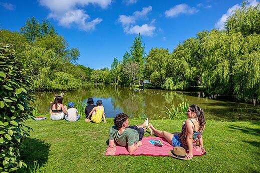 Familie ontspant aan een groene vijver op camping CAPFUN Cenic in PENESTIN (56).