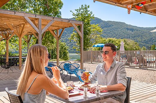 Koppel luncht op restaurantterras met uitzicht meer op camping CLICOCHIC Chancia (01).