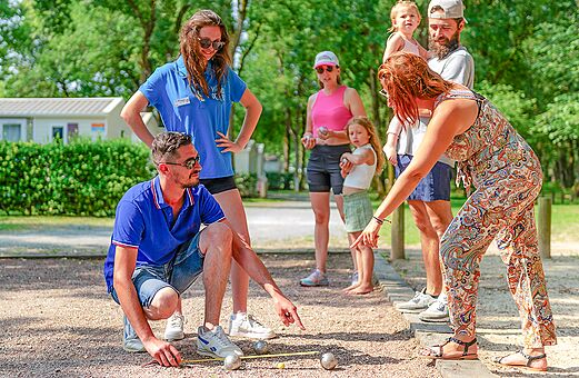 Familie en animator spelen jeu de boules op camping VAGUES OCEANES in Saint-Laurent-de-la-Prée (17).
