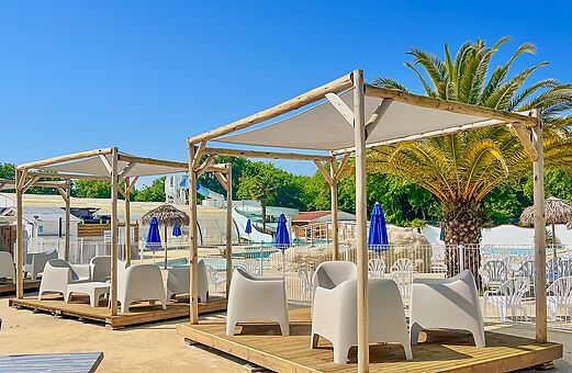 Zwembad, glijbanen en stoelen onder pergola's op camping VAGUES OCEANES Domaine les Charmilles in Saint-Laurent-de-la-Pr�e (17).