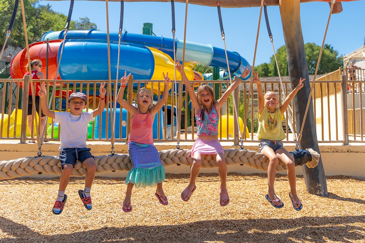 Lachende kinderen op schommel, waterglijbanen bij camping CLICOCHIC Ch�teau de Boisson (30).