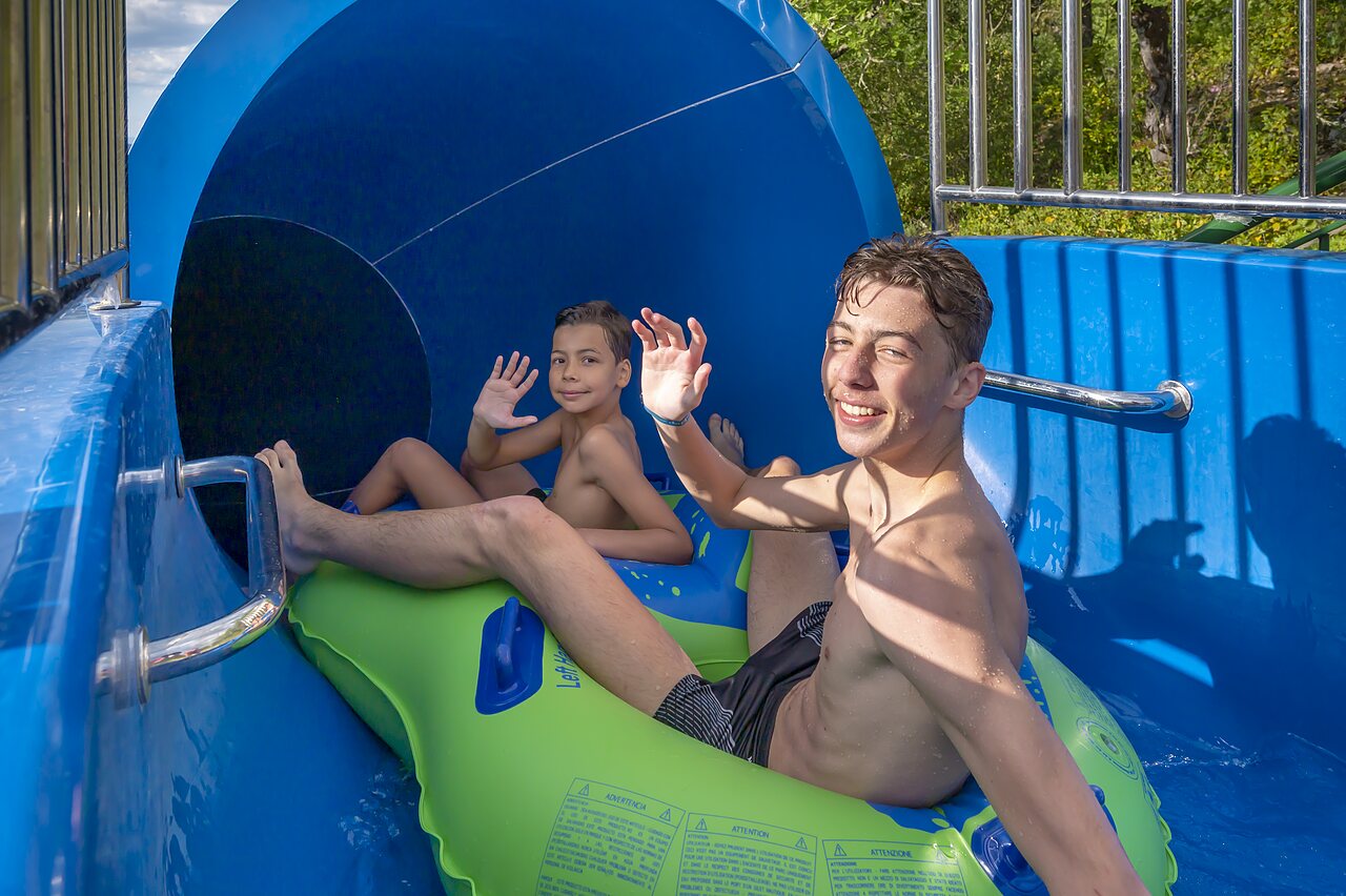 Waterglijbaan met lachende kinderen op een band op camping CLICOCHIC Ch�teau de Boisson in All�gre-les-Fumades (30).