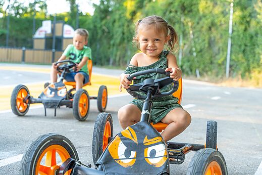 Lachende kinderen op skelters op camping CLICOCHIC Château de Boisson in Allègre-les-Fumades (30).