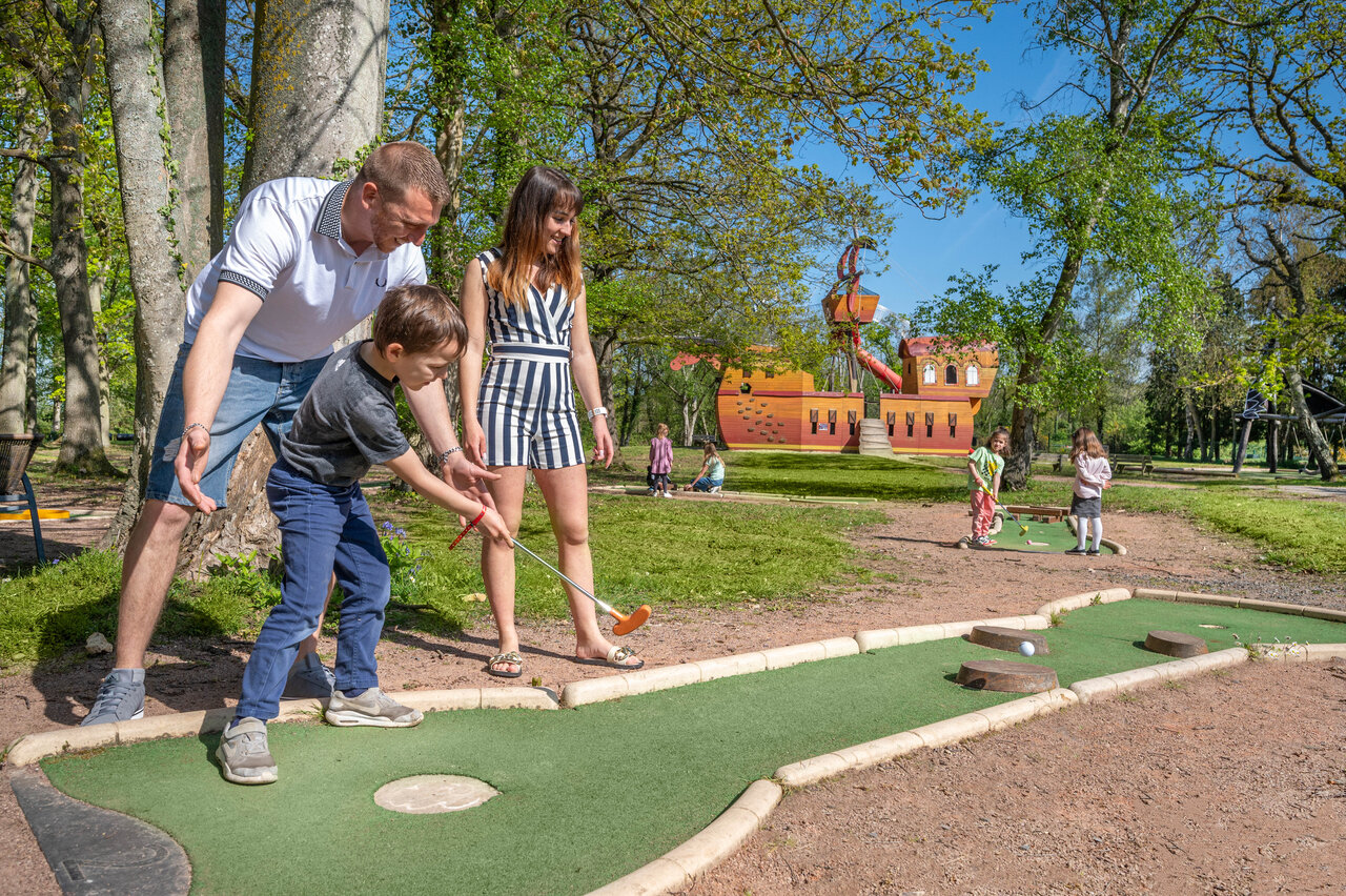 Familie speelt minigolf met speeltuin op camping CAPFUN Chateau d'Arvid in Villerville (14).
