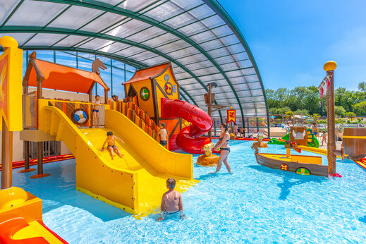 Overdekte waterspeeltuin met glijbanen en kinderen op CAPFUN Chateau d'Arvid in Villerville (14).