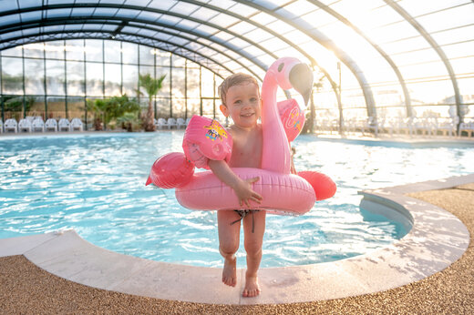 Overdekt zwembad, kind met roze flamingo zwemband, CAPFUN Chateau d'Arvid Villerville.