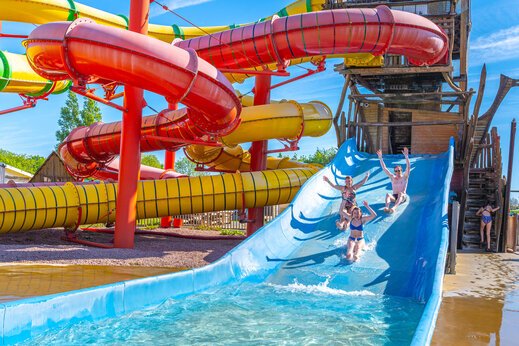 Kleurrijke waterglijbanen en mensen die plezier hebben op camping CAPFUN Chateau d'Arvid in Villerville.