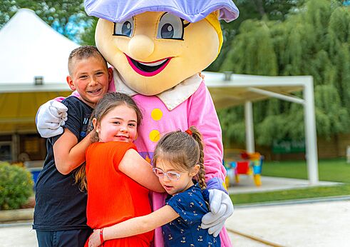 Campingmascotte knuffelt lachende kinderen op camping CAPFUN La Chênaie in PORNIC (44).