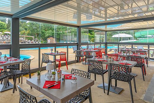 Modern restaurant met tafels en stoelen bij het zwembad op camping CAPFUN La Chênaie in PORNIC (44).