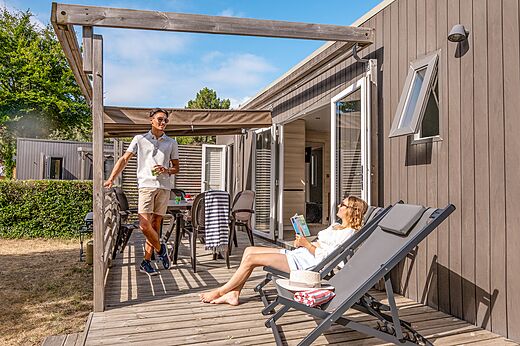 Moderne stacaravan met houten terras en stel op camping CLICOCHIC Chouans in SAINT HILAIRE DE RIEZ (85).
