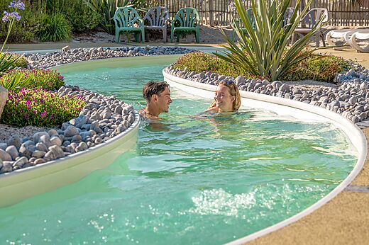 Zwembad lazy river met lachend stel op camping CLICOCHIC Chouans in SAINT HILAIRE DE RIEZ (85).