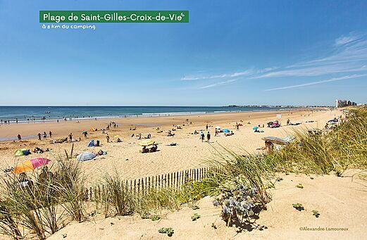Groot zandstrand in Saint-Gilles-Croix-de-Vie, Vendée, met zwemmers en parasols.