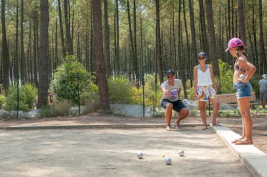 Familie speelt jeu de boules op een schaduwrijk terrein op camping VAGUES OCEANES Les Cigales in Moliets-Plage (40).