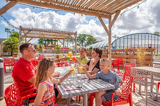 Familie met verfrissende drankjes aan de buitenbar van camping CAPFUN Citadelle de Loustic.