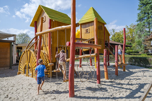 Houten speeltuin met kinderen op zand bij camping CAPFUN Citta di Angera VA.