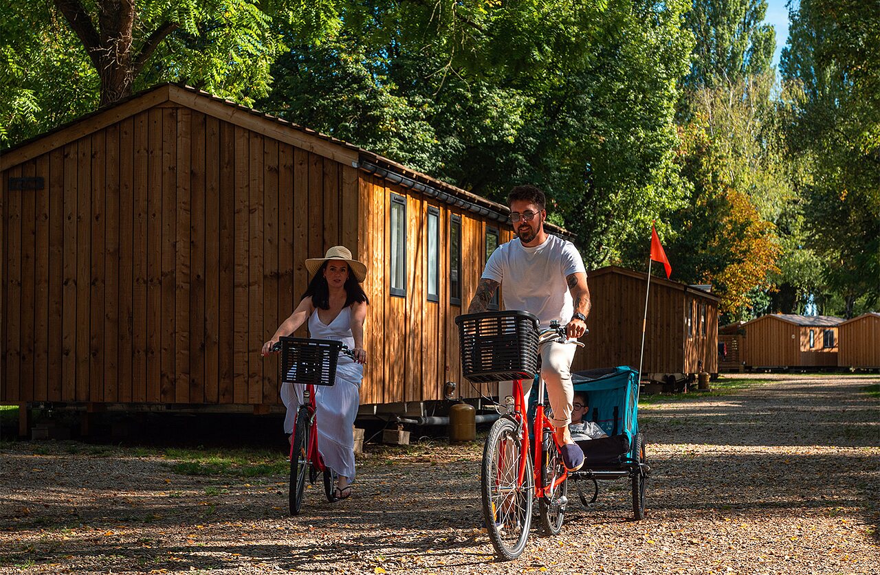 Koppel op fietsen met kinderkar voor accommodaties op camping CLICOCHIC Au Clair Ruisseau in Gerstheim (67).