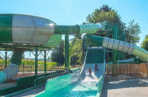 Reusachtige waterglijbanen en spelende kinderen op camping CLICOCHIC Au Clair Ruisseau in Gerstheim (67).