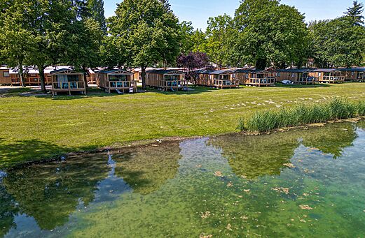 Houten stacaravans met terrassen aan het water op camping CLICOCHIC.