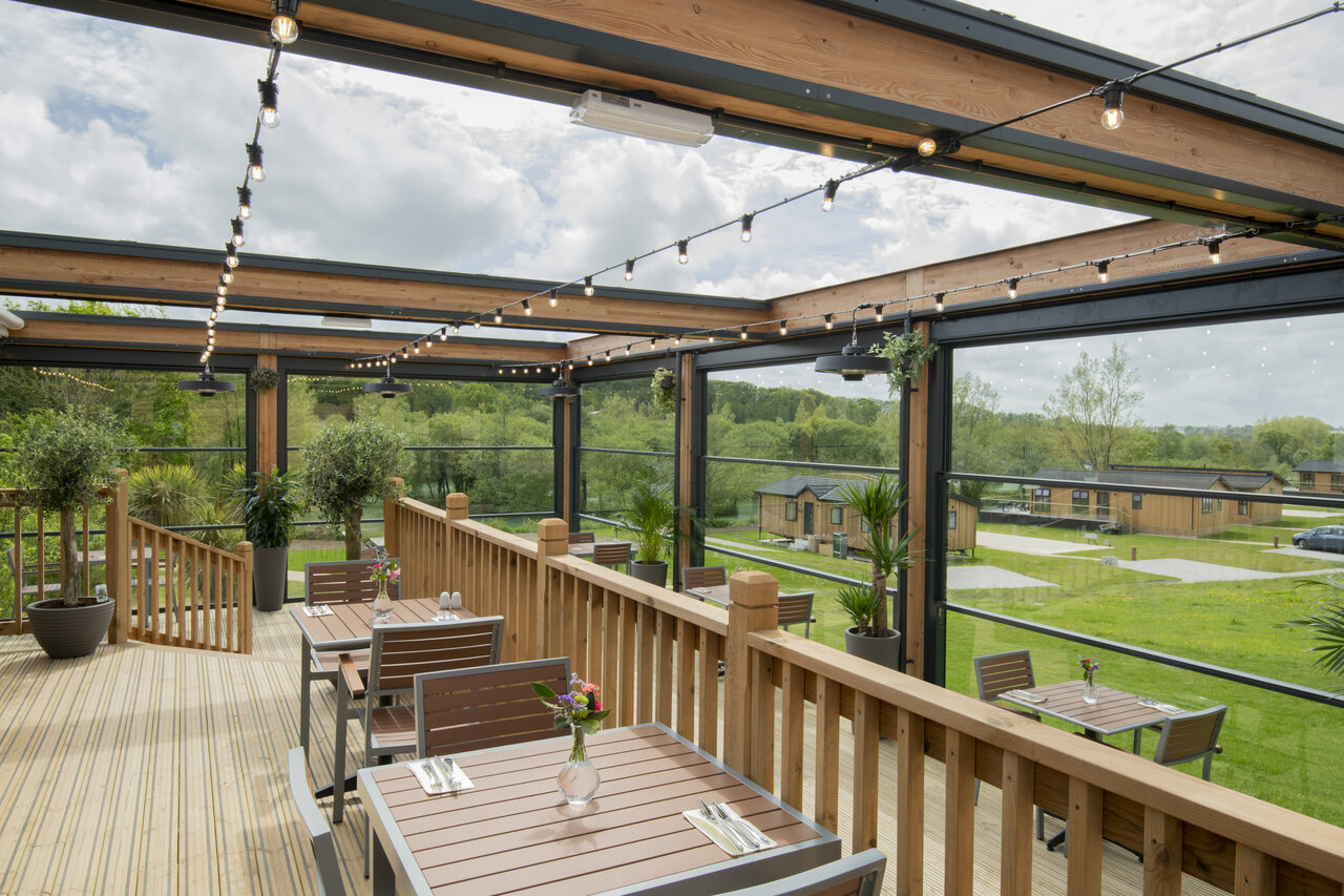 Buiten restaurantterras met tafels, uitzicht op lodges, CAPFUN UK Clawford Lakes.