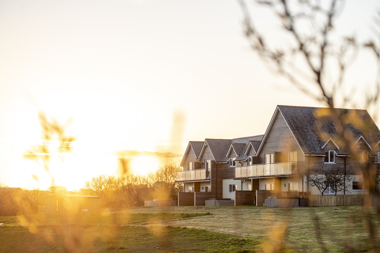 Moderne accommodaties met balkons bij zonsondergang op camping CAPFUN UK Clawford Lakes.