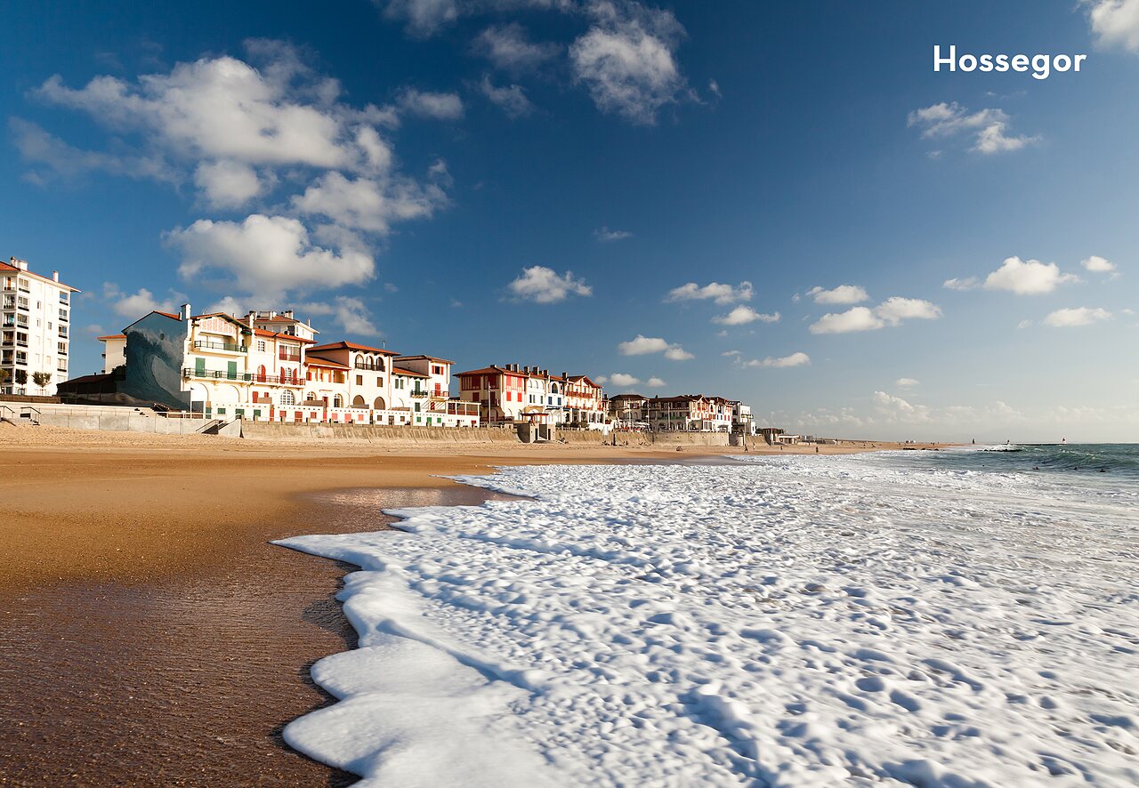 Strand van Hossegor met golven en kleurrijke gebouwen, te bezoeken plek nabij de camping.