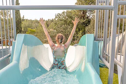 Vrouw op waterglijbaan, armen omhoog, op camping CLICOCHIC Commanderie in Rustiques.