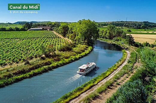 Boot vaart op het Canal du Midi, omringd door wijngaarden en natuur.