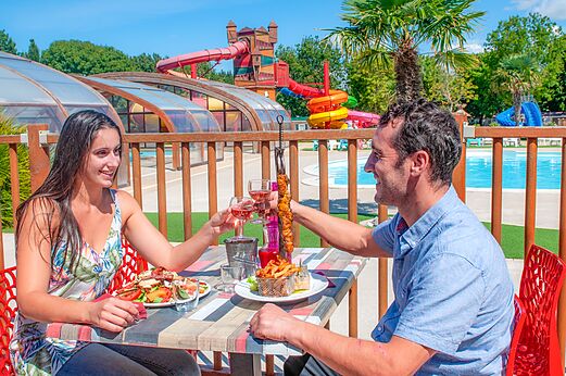 Koppel dineert, waterglijbanen op camping CAPFUN Coquelicots in Royan (17).