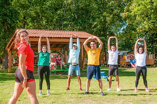 Groep volwassenen doet buiten stretchoefeningen op camping CAPFUN Coquelicots in Royan (17).