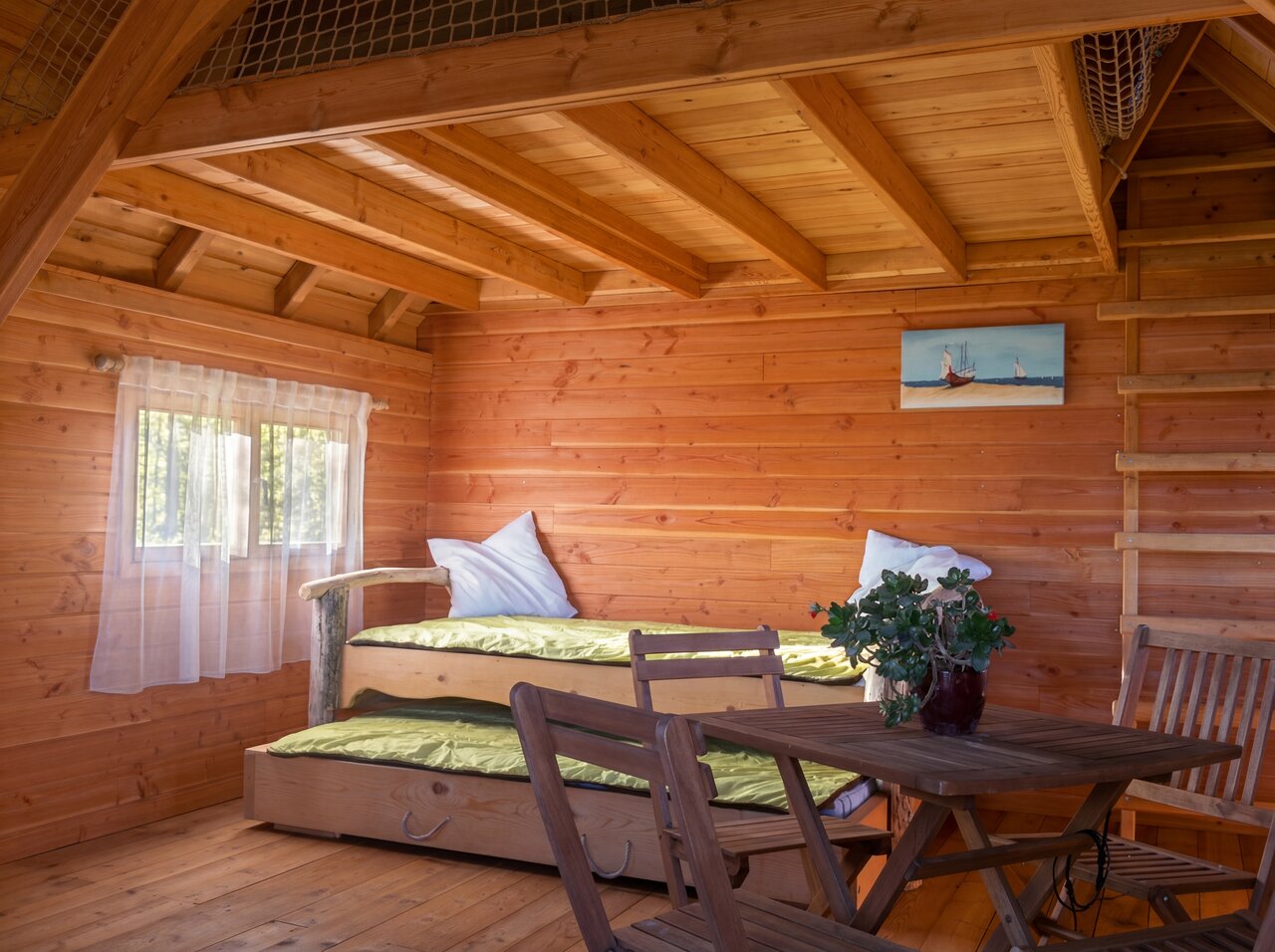 Interieur houten hut met uitschuifbedden en tafel op camping CAPFUN C�te Vermeille: Cabane dans les airs in Port La Nouvelle (11).