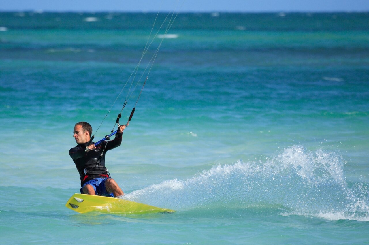 Man kitesurfend op turquoise water, dynamische spetters op camping CAPFUN C�te Vermeille : Cabane dans les airs � Port La Nouvelle (11).