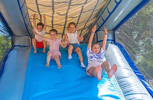 Kinderen spelen op een opblaasbare glijbaan op camping CLICOCHIC Couriou in Recoubeau-Jansac.
