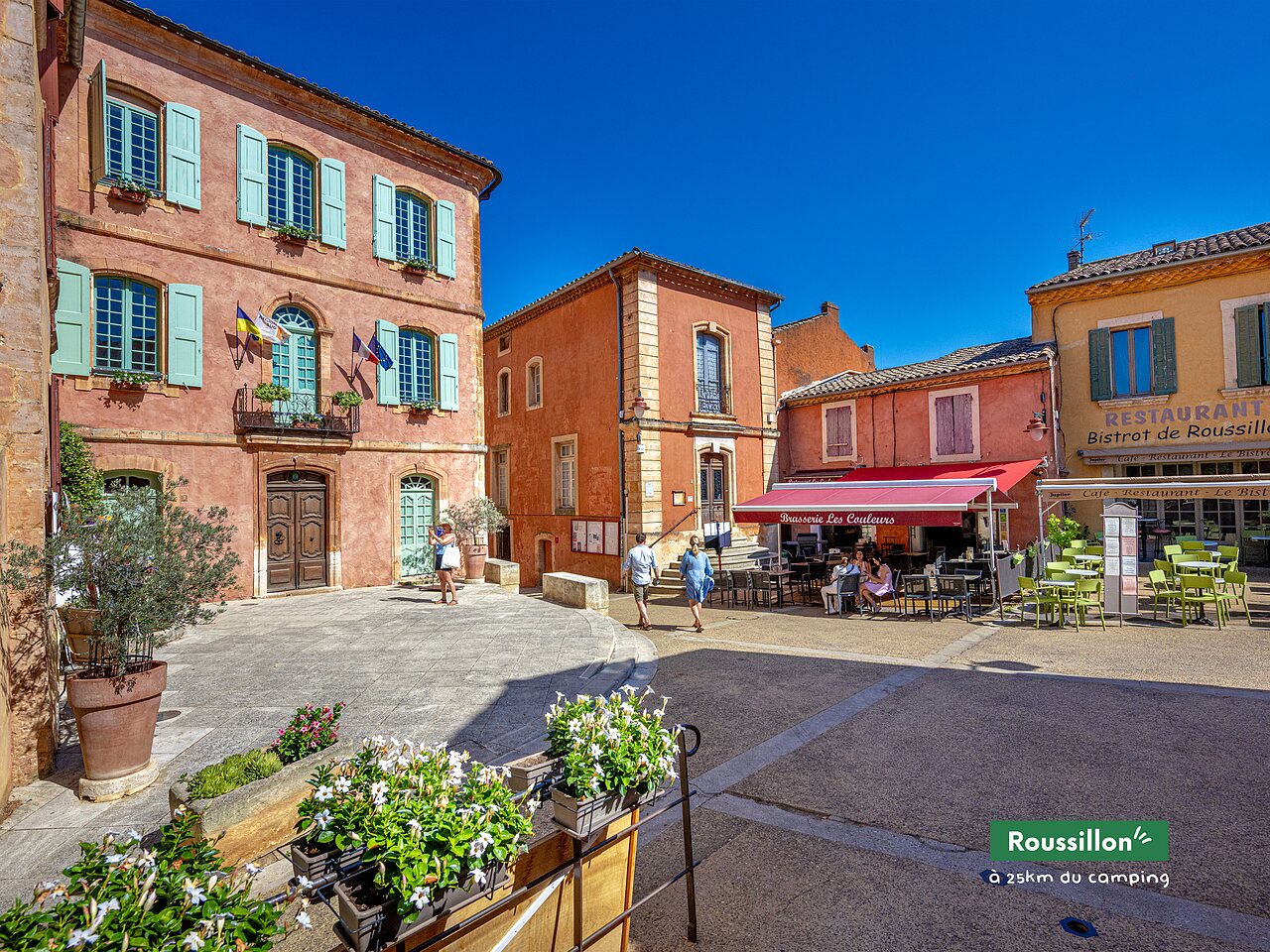 Centraal plein van het dorp Roussillon, kleurrijke huizen en restaurant in de Provence.