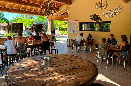 Overdekt restaurant- en bargedeelte met families op camping CLICOCHIC Coutelière (84).
