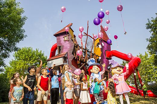 Kinderen en mascottes bij kleurrijke speeltuin met glijbanen op camping CAPFUN Curty's in Jard sur Mer (85).