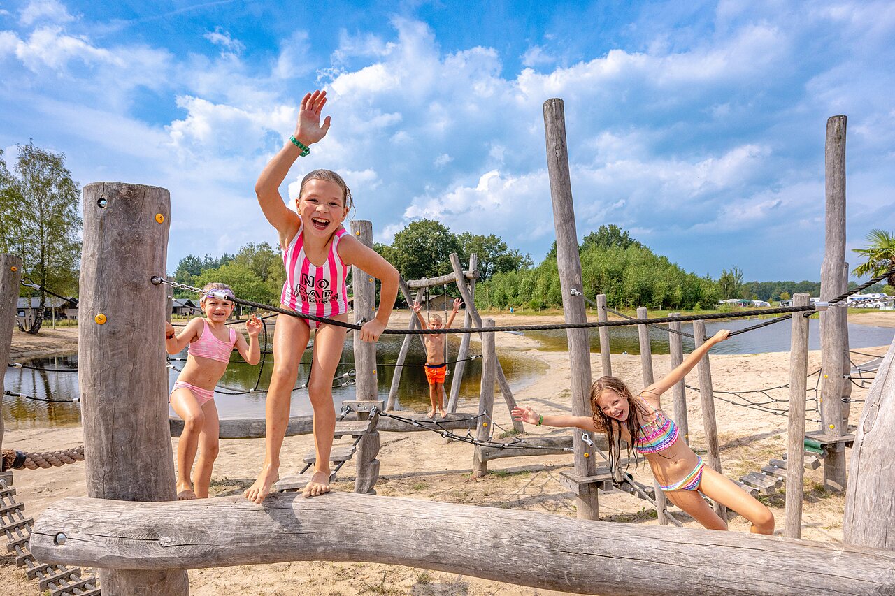 Kinderen op houten speeltoestellen, zandstrand op camping CAPFUN De Belten in Rheeze.