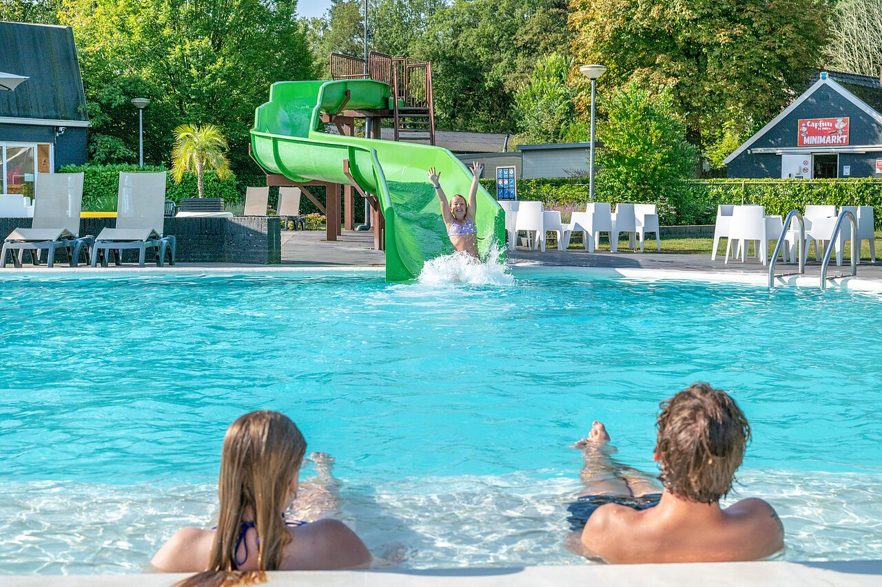 Waterglijbaan en buitenzwembad met spelende kinderen op camping CAPFUN De Belten in Rheeze.