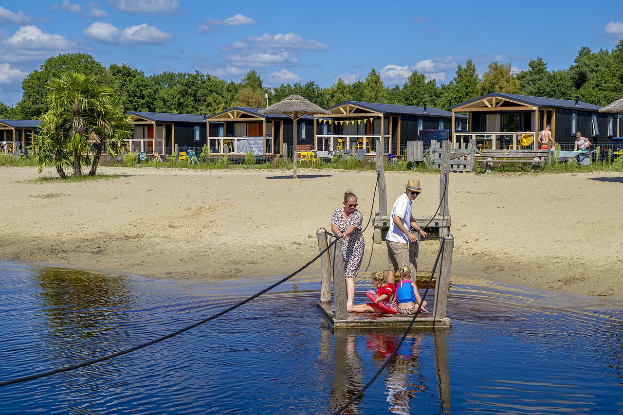 Familie op vlot, zandstrand en accommodaties op camping CAPFUN De Belten in Rheeze.