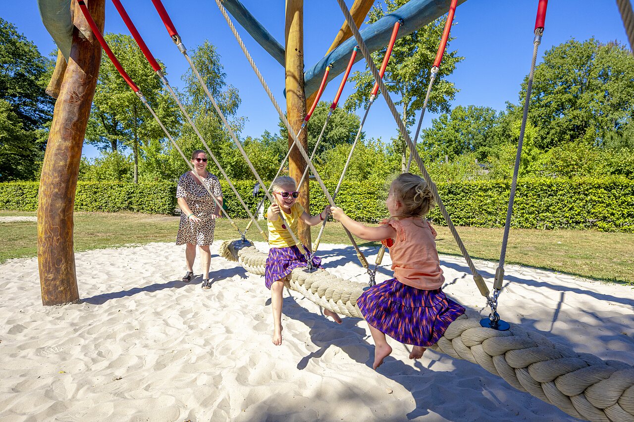 Twee kinderen spelen op een reuzenkabel schommel op camping CAPFUN De Belten in Rheeze.