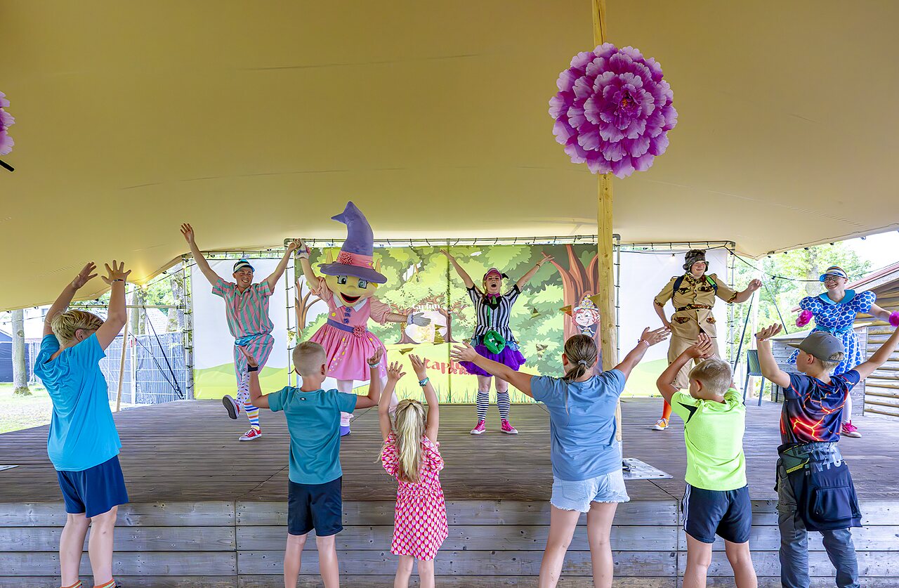 Kinderen doen mee aan animatieshow met mascottes op podium, camping CAPFUN De Belten Rheeze.
