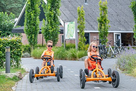 Lachende kinderen op oranje skelters op camping CAPFUN De Belten in Rheeze.